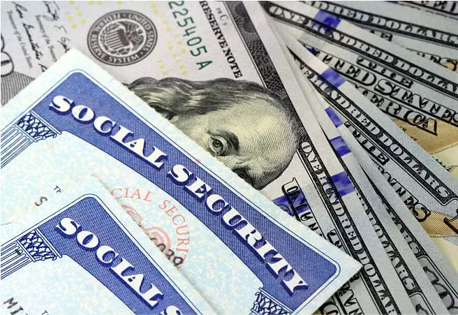 Close-up of social security cards and various U.S. dollar bills, including a $20 bill featuring Andrew Jackson, spread out on a surface.